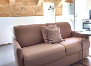 a brown couch with a pillow on it in a living room at Ripple 23 Savynomad Harbour Residences in Valletta