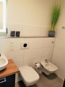 a white bathroom with a toilet and a sink at Ferienwohnung MeerZeit EG in Altefähr