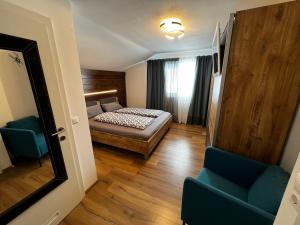 a bedroom with a bed and two blue chairs at Haus Bergfeld with the view over Dachstein in Ramsau am Dachstein