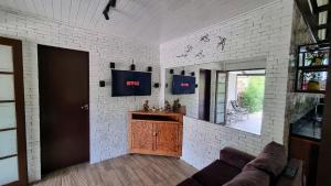 a living room with a couch and a tv on a white brick wall at Casa do Beija-Flor in Florianópolis