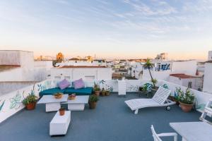 a rooftop patio with white furniture and potted plants at La Cocotera Boutique Hostel & Coworking in Tarifa