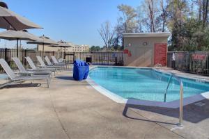 una piscina con sillas y sombrilla en TownePlace Suites by Marriott Albany, en Albany