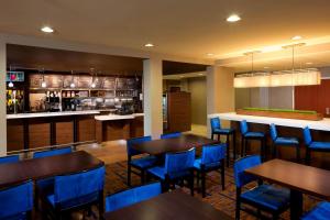 a restaurant with tables and blue chairs and a bar at Courtyard by Marriott Brownsville in Brownsville