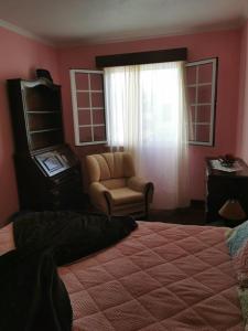 um quarto com uma cama, uma cadeira e uma janela em Silvia's House em Ponta Delgada