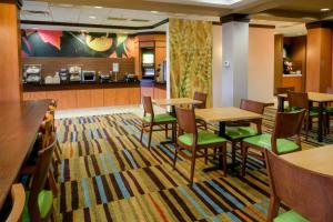 a restaurant with tables and chairs and a kitchen at Fairfield Inn & Suites Kennett Square in Kennett Square