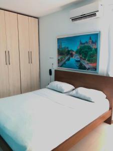 ein Schlafzimmer mit einem großen weißen Bett mit einem Gemälde an der Wand in der Unterkunft Hotel Suites Caribe in Barranquilla
