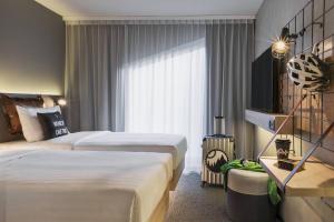 Cette chambre comprend 2 lits et une fenêtre. dans l'établissement Moxy Lausanne City, à Lausanne