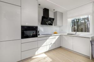 a white kitchen with white cabinets and a window at 3-bedroom Apartment - Lesne Tarasy by Renters Prestige in Dziwnówek