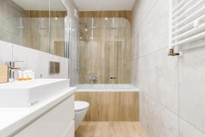 a bathroom with a tub and a toilet and a sink at 3-bedroom Apartment - Lesne Tarasy by Renters Prestige in Dziwnówek