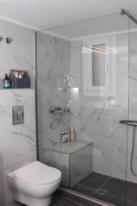 y baño blanco con aseo y ducha. en Noema Urban Apartment, en Kavala