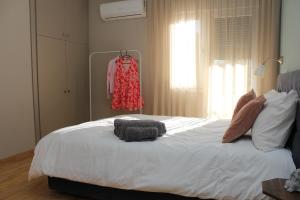 Un dormitorio con una cama blanca con un vestido rojo en un estante en Noema Urban Apartment, en Kavala