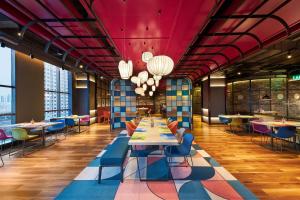 a dining room with tables and chairs and windows at Aloft Shijiazhuang in Shijiazhuang
