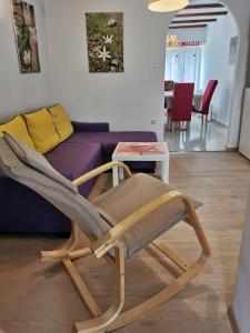 a wooden chair in a living room with a purple couch at Guesthouse Stivan (920) in Cres