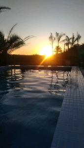 a swimming pool with the sunset in the background at Apt próximo à praia de Ponta Negra/Litoral Sul/Natal in Parnamirim