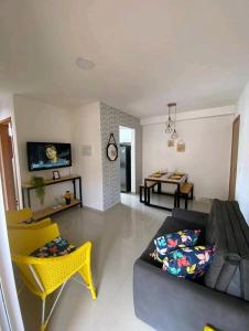 uma sala de estar com um sofá e cadeiras amarelas em Apt próximo à praia de Ponta Negra/Litoral Sul/Natal em Parnamirim