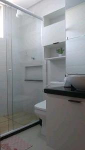 uma casa de banho com uma cabina de duche em vidro e um WC. em Apt próximo à praia de Ponta Negra/Litoral Sul/Natal em Parnamirim