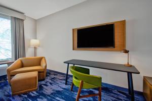 Habitación de hotel con escritorio, silla y TV. en Fairfield by Marriott Inn & Suites Orlando at FLAMINGO CROSSINGS® Town Center, en Orlando