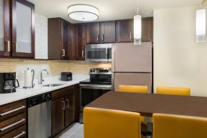 una cocina con electrodomésticos de acero inoxidable y armarios de madera en Residence Inn Rochester Henrietta, en Rochester