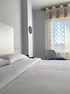a bedroom with a bed and a chair and a window at Lemos Estrella in Monforte de Lemos