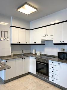 a kitchen with white cabinets and a sink at Lemos Estrella in Monforte de Lemos