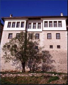 un gran edificio de ladrillo con un árbol delante de él en Vergoula's Mansion en Kastoria