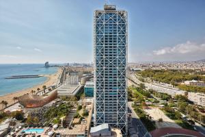ein hohes Gebäude neben einem Strand und dem Meer in der Unterkunft Hotel Arts Barcelona in Barcelona
