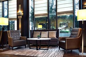 eine Lobby mit Stühlen, einem Tisch und Fenstern in der Unterkunft Sheraton Essen Hotel in Essen