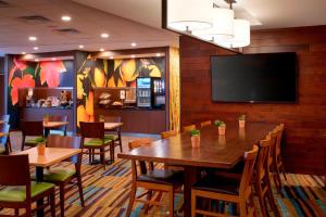 Fairfield Inn & Suites By Marriott Ann Arbor Ypsilanti في إبسيلانتي: مطعم بطاولات وكراسي وتلفزيون بشاشة مسطحة