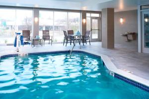 una piscina en una habitación de hotel con mesa y sillas en Fairfield Inn & Suites By Marriott Ann Arbor Ypsilanti en Ypsilanti