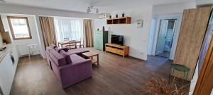 a living room with a purple couch and a kitchen at C&Y Zev Apartments in Mamaia