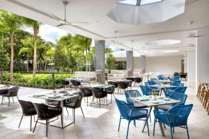 un restaurante con mesas, sillas y palmeras en Le Méridien Dania Beach at Fort Lauderdale Airport, en Avon Park
