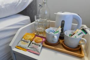 a tray with cups and drinks on a bed at Rooms at Rolleston in Rolleston