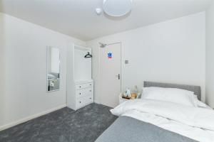 a white bedroom with a bed and a mirror at Rooms at Rolleston in Rolleston