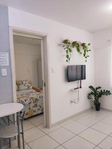 Edificio Gales Pajuçara Apartmento في ماسيو: غرفة بها تلفزيون وسرير وطاولة