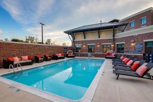 薩默維爾的住宿－Residence Inn by Marriott Charleston Summerville，砖砌建筑旁的一个带沙发和椅子的游泳池
