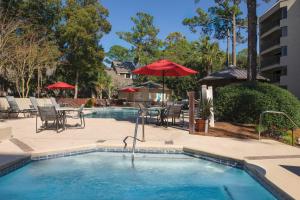 uma piscina com mesas e cadeiras e um guarda-sol em Marriott's Heritage Club em Hilton Head Island