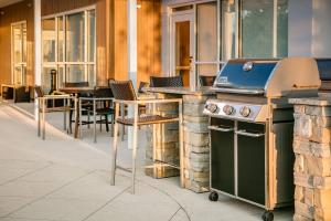 an outdoor kitchen with a grill and tables and chairs at TownePlace Suites by Marriott Kansas City Airport in Kansas City