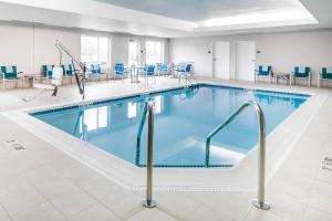 a pool with blue chairs and tables in a building at TownePlace Suites by Marriott Kansas City Airport in Kansas City