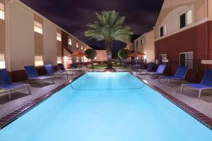 una grande piscina con sedie e una palma di TownePlace Suites by Marriott Lake Jackson Clute a Clute