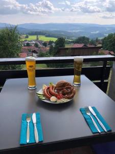 uma mesa com um prato de comida e dois copos de cerveja em Apartment Tälerblick Maxi -neu modernisiert- em Böbrach