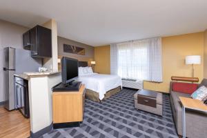a hotel room with a bed and a flat screen tv at TownePlace Suites by Marriott East Lansing in East Lansing