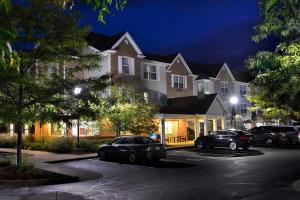 a group of houses with cars parked in a parking lot at TownePlace Suites by Marriott East Lansing in East Lansing
