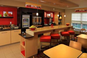 uma cozinha com paredes vermelhas e um balcão com bancos de bar em TownePlace Suites by Marriott East Lansing em East Lansing