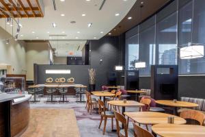 a restaurant with wooden tables and chairs and windows at Courtyard by Marriott New York Queens/Fresh Meadows in Queens