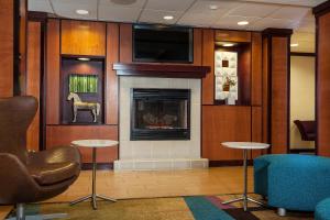 Fairfield Inn & Suites by Marriott Anchorage Midtown في أنكوراج: لوبي فيه موقد وكراسي وتلفزيون