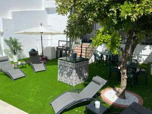 un patio con sillas, un árbol y una sombrilla en Esencia Andalucia en Rociana
