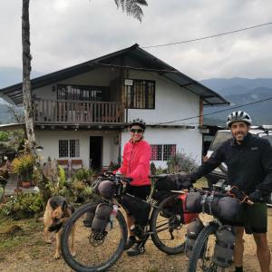 Hostal de la montaña ecoturismo في Mocoa: رجل وامرأه بدراجتهم امام المنزل
