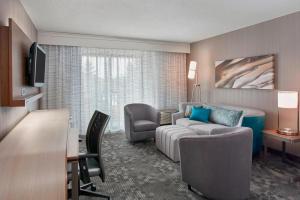 a living room with a couch and a chair in a hotel room at Courtyard by Marriott Detroit Pontiac/Auburn Hills in Pontiac