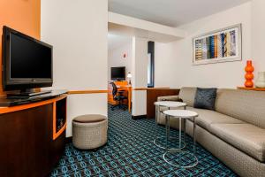 a hotel room with a couch and a flat screen tv at Fairfield by Marriott Wilkes-Barre in Wilkes-Barre
