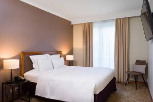 a hotel room with a white bed and a television at Marriott Executive Apartments Brussels in Brussels